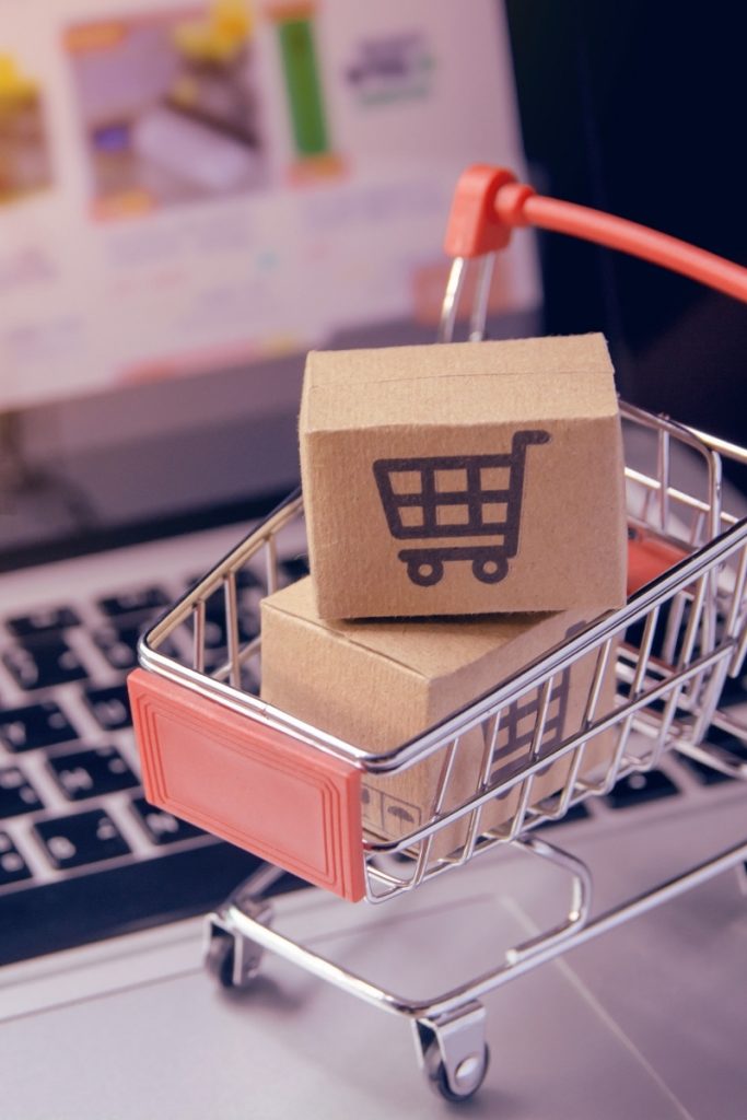 A toy shopping cart filled with boxes resting on laptop keys